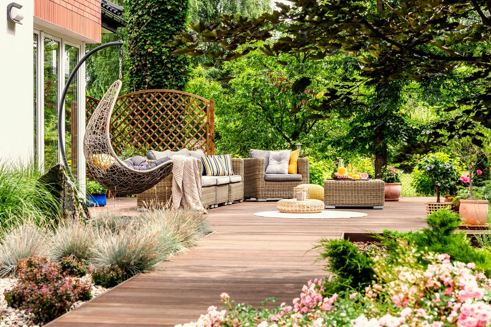Terrasse extérieure aménagée avec salon de jardin en résine tressée comprenant canapé modulaire, fauteuils et table basse