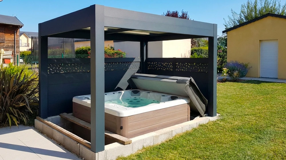 Spa balnéo encastré dans une dalle béton, installé sous une pergola bioclimatique en aluminium anthracite avec lames orientables et claustra décoratif ajouré