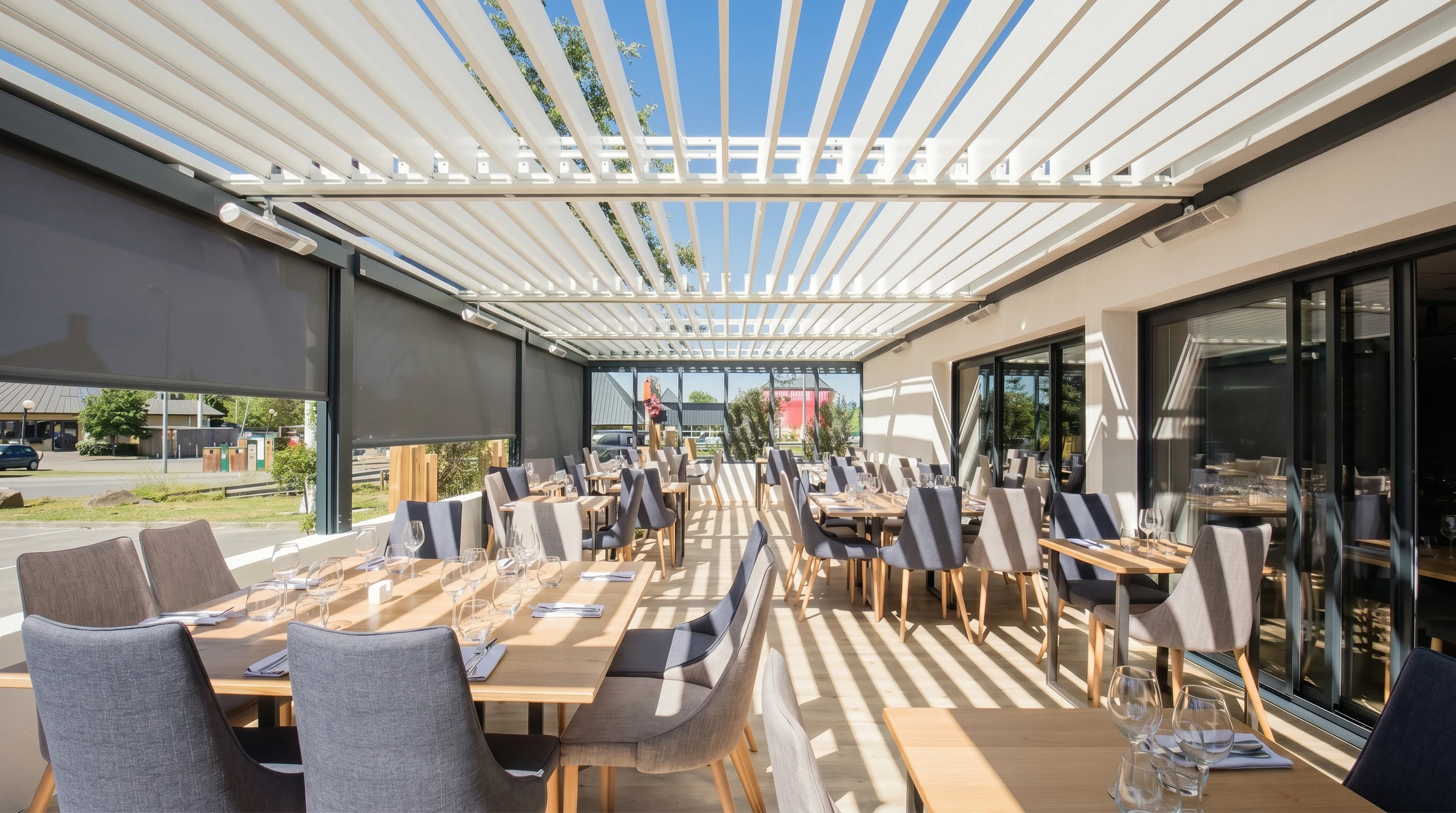 Espace extérieur contemporain avec pergola bioclimatique à lames orientables noires abritant un salon de jardin en résine tressée