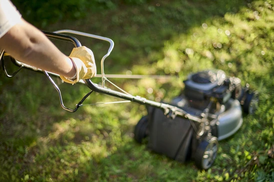Jardinier professionnel en combinaison de protection verte utilisant une débroussailleuse thermique pour l'entretien d'espaces verts